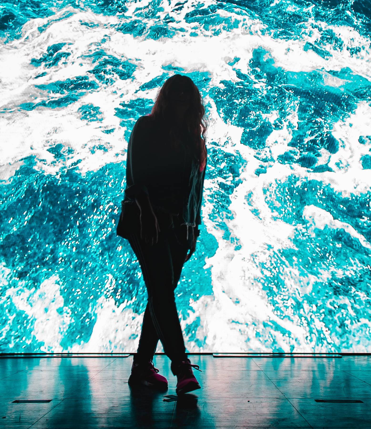 A woman standing in front of a digital display signage.
